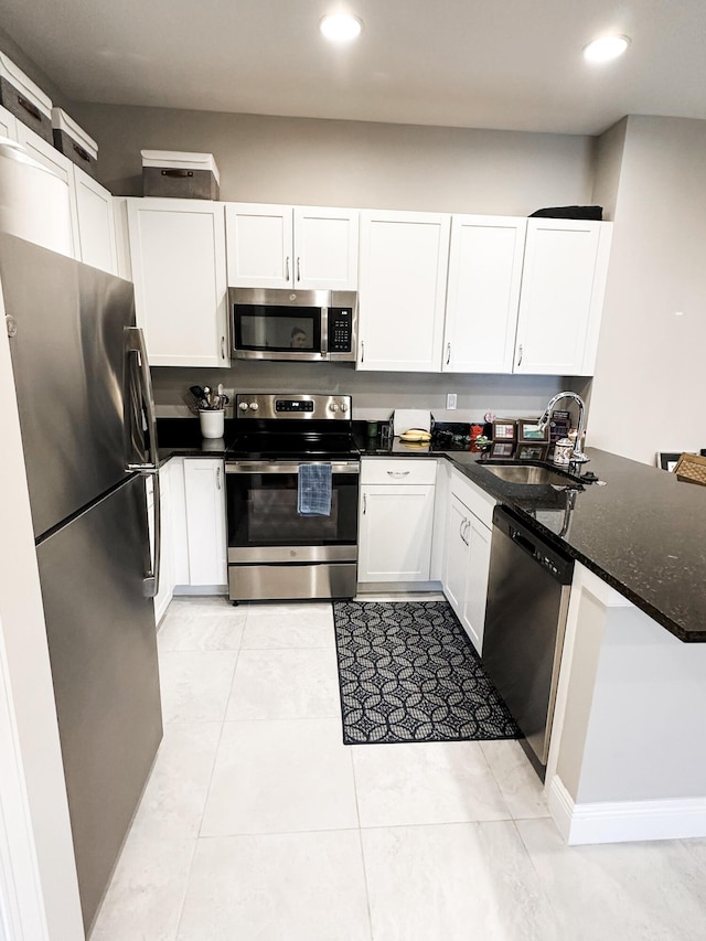 kitchen with white cabinetry, dark stone counters, light tile patterned floors, sink, and stainless steel appliances