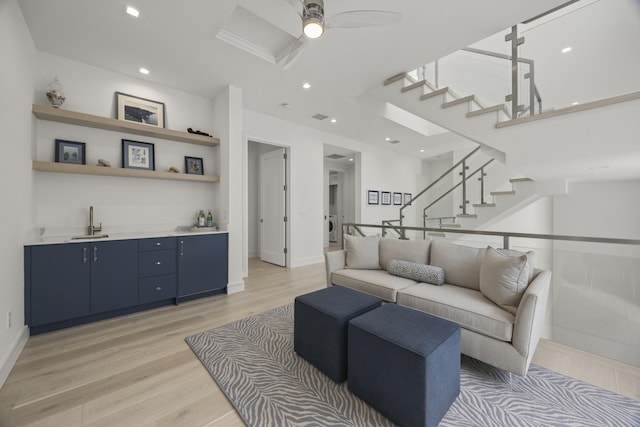 living room featuring ceiling fan, sink, and light hardwood / wood-style flooring