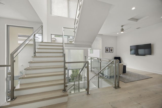 stairs with ceiling fan, a wealth of natural light, and hardwood / wood-style flooring