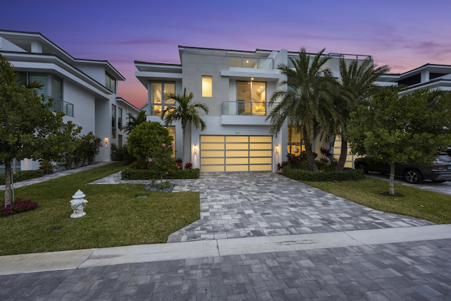 view of front of home with a yard, a garage, and a balcony