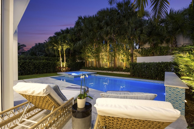 pool at dusk featuring an in ground hot tub