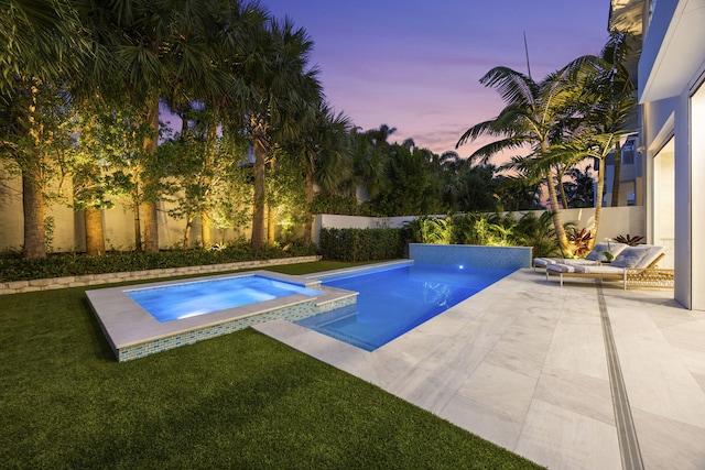 pool at dusk featuring an in ground hot tub, a lawn, and a patio