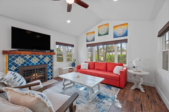 living room with ceiling fan, a tile fireplace, vaulted ceiling, and dark hardwood / wood-style floors