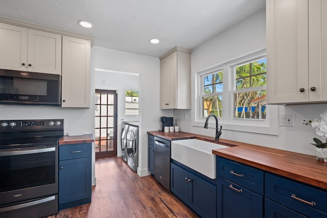 kitchen featuring stainless steel appliances, wooden counters, blue cabinetry, white cabinets, and separate washer and dryer