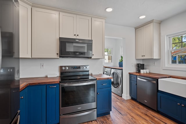 kitchen featuring wooden counters, blue cabinetry, washer / dryer, dark hardwood / wood-style flooring, and appliances with stainless steel finishes