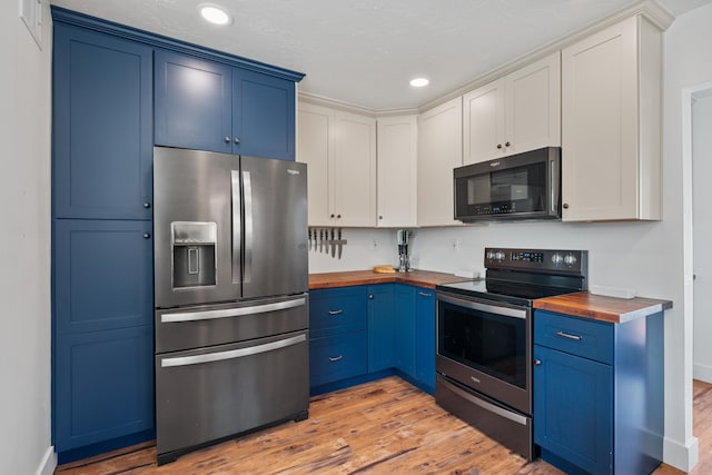 kitchen featuring white cabinets, appliances with stainless steel finishes, and wood counters