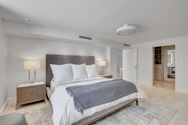 bedroom with a walk in closet, light hardwood / wood-style flooring, and a closet