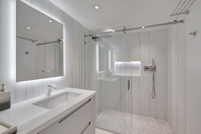 bathroom featuring a shower with door and vanity