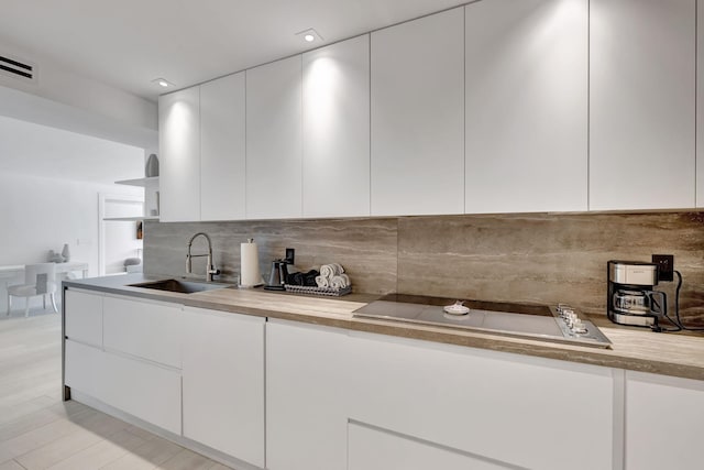 kitchen with white cabinets, backsplash, and sink