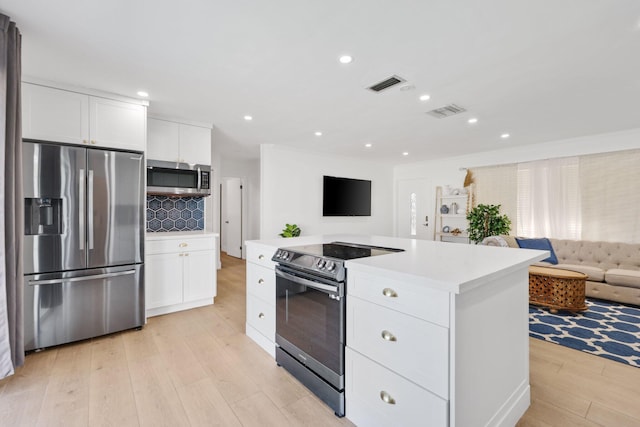 kitchen featuring decorative backsplash, stainless steel appliances, white cabinets, a center island, and light hardwood / wood-style floors