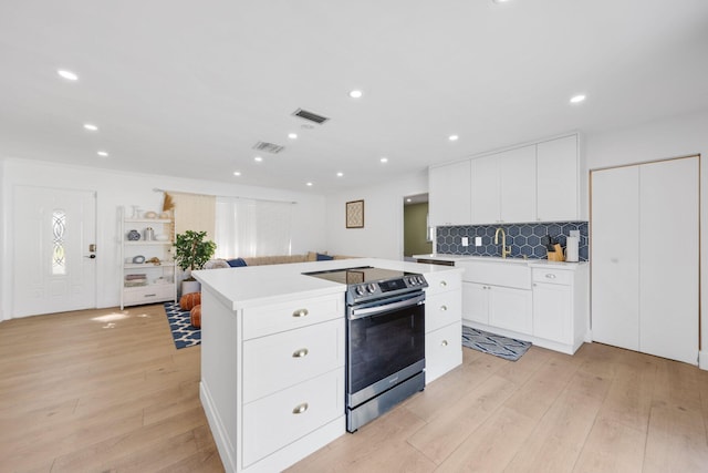 kitchen with white cabinetry, tasteful backsplash, stainless steel range with electric stovetop, a kitchen island, and light wood-type flooring