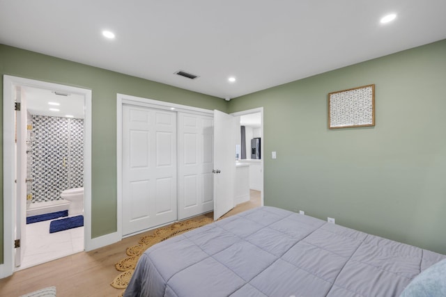 bedroom featuring light wood-type flooring, connected bathroom, and a closet