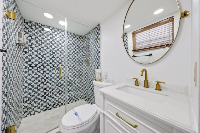 bathroom featuring vanity, a shower with shower door, and toilet