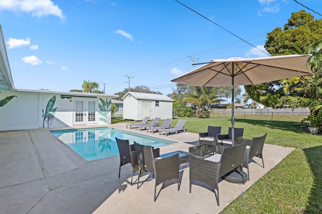 view of swimming pool featuring a storage unit, a yard, a patio, and french doors