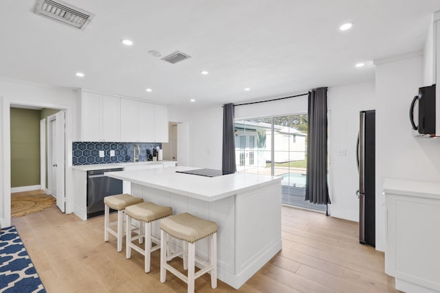 kitchen featuring black appliances, a kitchen island, tasteful backsplash, light hardwood / wood-style floors, and white cabinetry