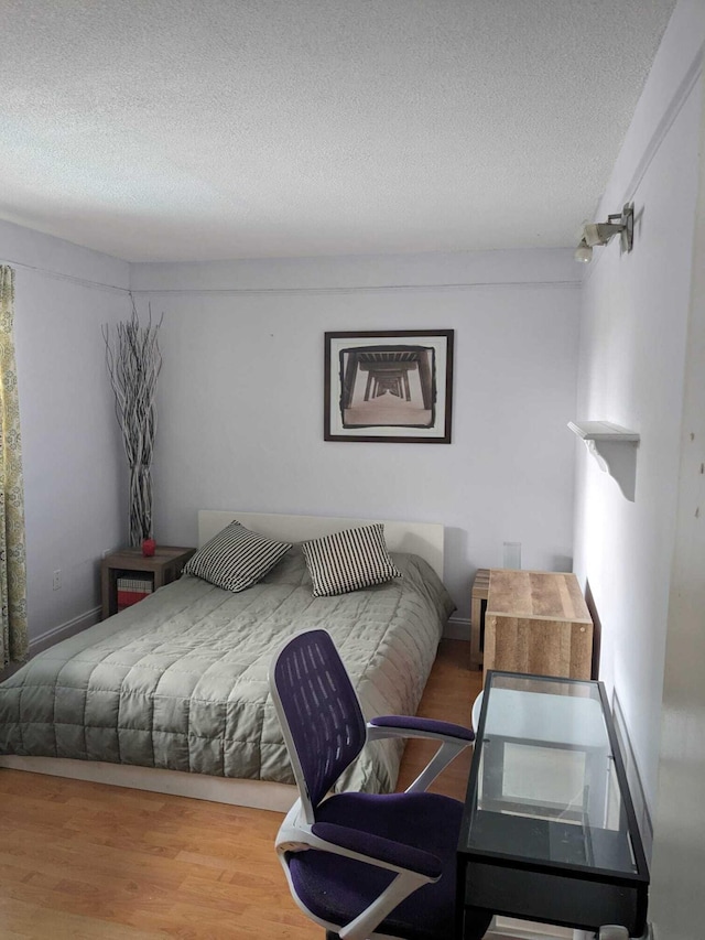 bedroom with a textured ceiling and hardwood / wood-style floors