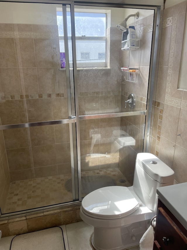 bathroom featuring tile walls, vanity, tile patterned floors, toilet, and walk in shower