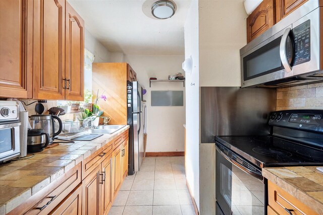 kitchen featuring light tile patterned floors, tile counters, tasteful backsplash, and appliances with stainless steel finishes