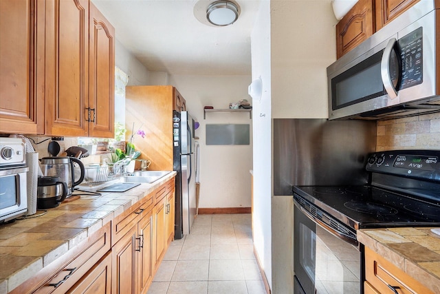 714 NE 10th St Unit 205, Hallandale Beach, FL 33009 - kitchen featuring tile counters, stainless steel appliances, tasteful backsplash, light tile patterned flooring, and brown cabinetry