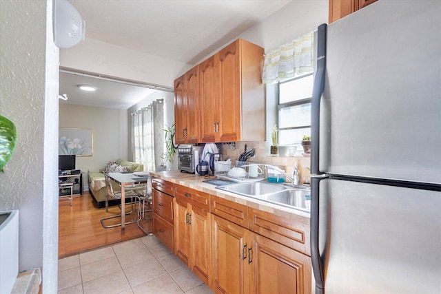 714 NE 10th St Unit 205, Hallandale Beach, FL 33009 - kitchen with freestanding refrigerator, a sink, light countertops, light tile patterned floors, and brown cabinets