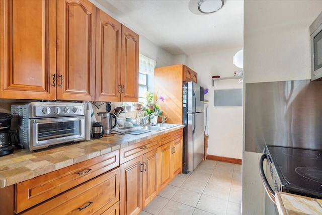 714 NE 10th St Unit 205, Hallandale Beach, FL 33009 - kitchen featuring electric range, freestanding refrigerator, tile counters, brown cabinetry, and light tile patterned flooring
