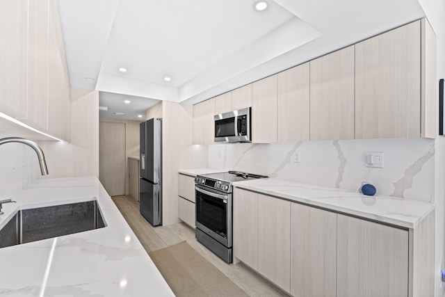 kitchen featuring stainless steel appliances, sink, tasteful backsplash, and light stone countertops