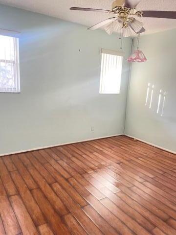 empty room with hardwood / wood-style floors and ceiling fan