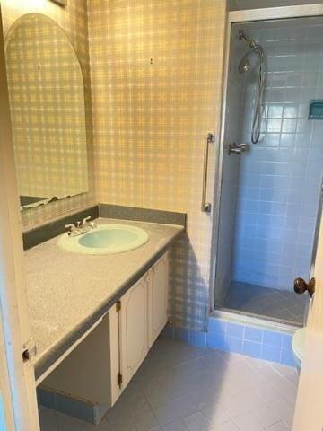 bathroom featuring toilet, vanity, tile patterned floors, and an enclosed shower