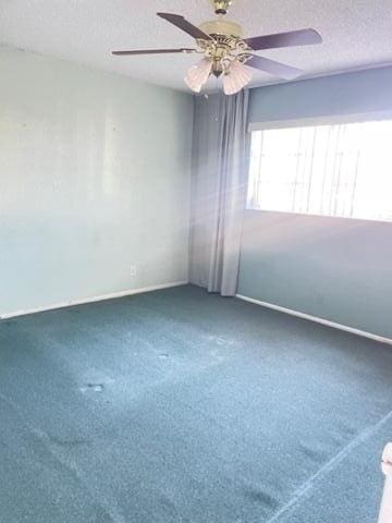 carpeted spare room with a textured ceiling and ceiling fan