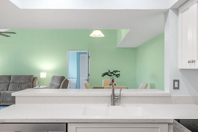 interior space featuring pendant lighting, dishwashing machine, white cabinetry, and sink