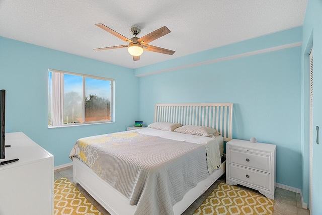 bedroom with light tile patterned floors, a textured ceiling, and ceiling fan