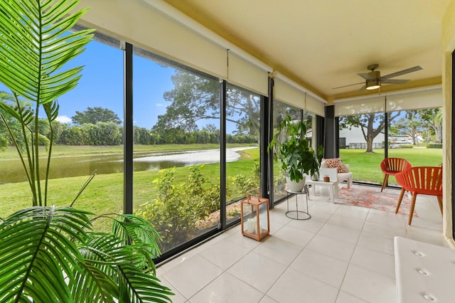 unfurnished sunroom featuring a ceiling fan and a water view