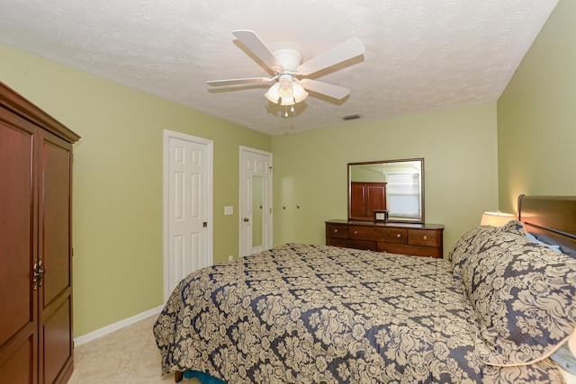 bedroom featuring ceiling fan, a textured ceiling, and two closets