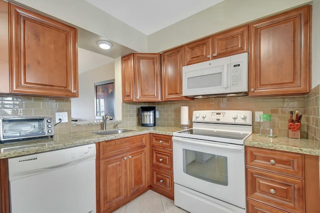 kitchen featuring white appliances, light stone countertops, tasteful backsplash, and sink