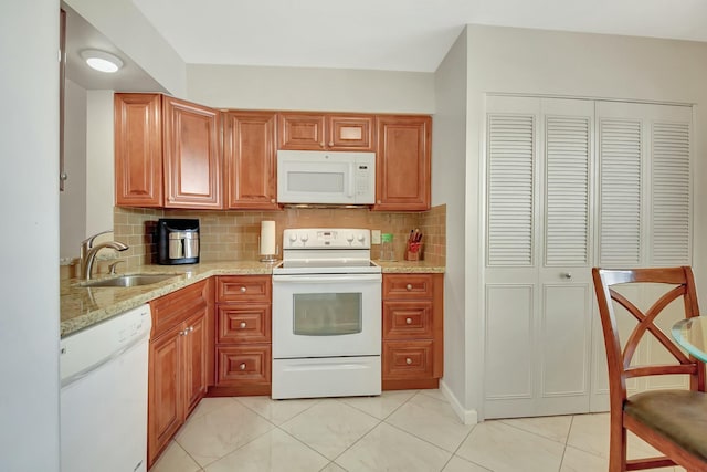 kitchen featuring white appliances, light stone countertops, light tile patterned floors, sink, and tasteful backsplash