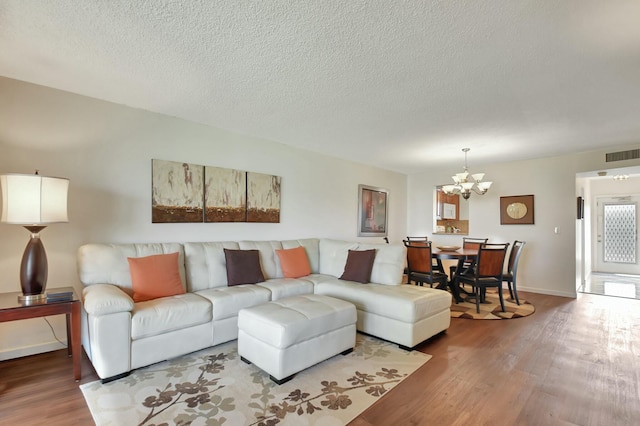 living room with wood-type flooring, a textured ceiling, and a notable chandelier