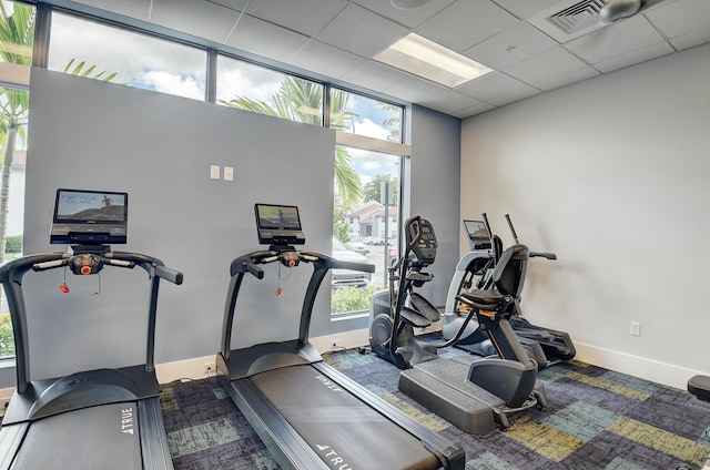 workout area with a drop ceiling and a wealth of natural light