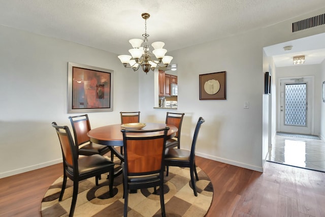 dining room with a textured ceiling, a notable chandelier, and hardwood / wood-style floors