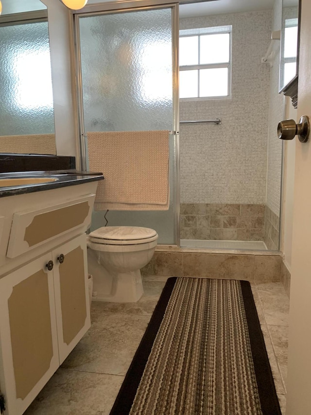 bathroom featuring vanity, toilet, tile patterned flooring, and a shower with door