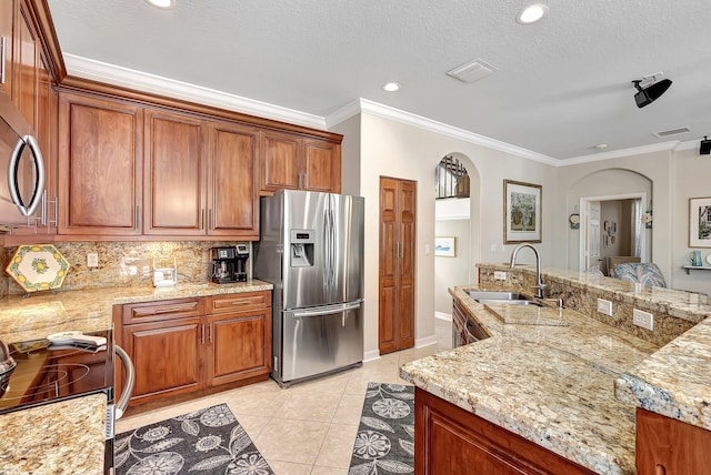 kitchen with tasteful backsplash, appliances with stainless steel finishes, light tile patterned flooring, arched walkways, and a sink