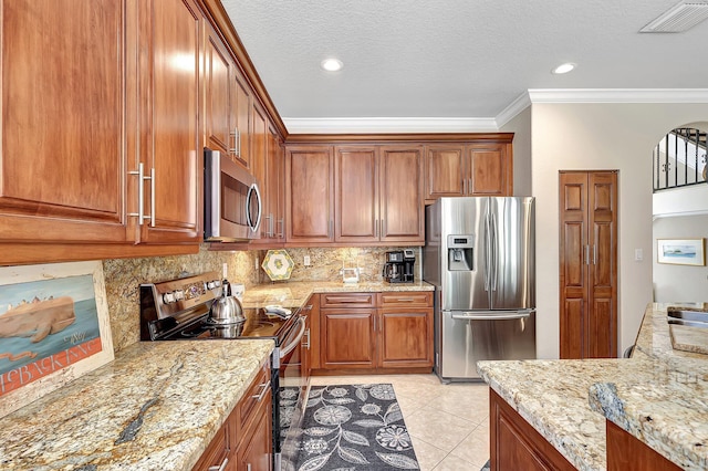 kitchen with light stone counters, ornamental molding, appliances with stainless steel finishes, brown cabinets, and backsplash