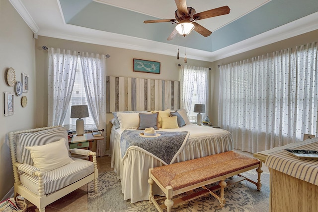 bedroom featuring a tray ceiling, multiple windows, and crown molding