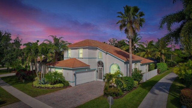 mediterranean / spanish-style house with a garage and a lawn