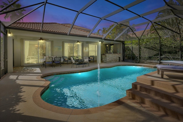 pool at dusk featuring an outdoor pool, a patio, and ceiling fan