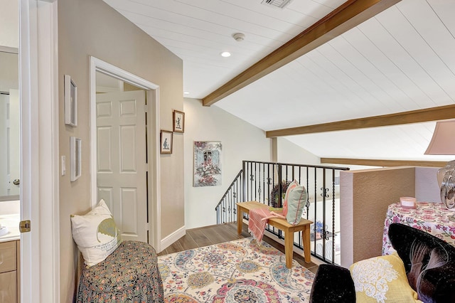 living area with lofted ceiling with beams, visible vents, an upstairs landing, and wood finished floors