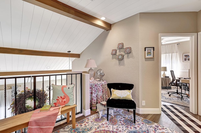 sitting room with vaulted ceiling with beams, wood finished floors, baseboards, and a textured wall