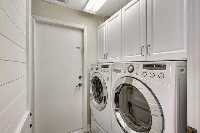 laundry area featuring washer and dryer, cabinet space, and a textured ceiling