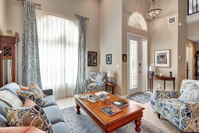 living room featuring light tile patterned floors, visible vents, a wealth of natural light, and a chandelier