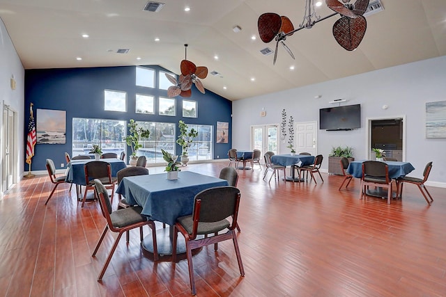 dining area with wood finished floors, visible vents, and high vaulted ceiling