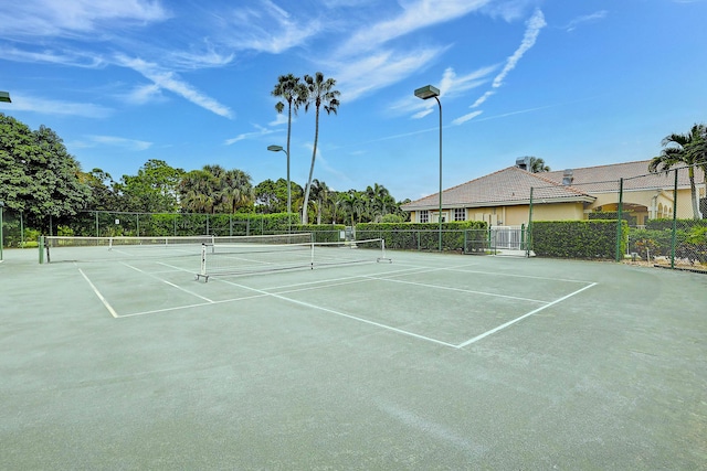 view of tennis court with community basketball court and fence